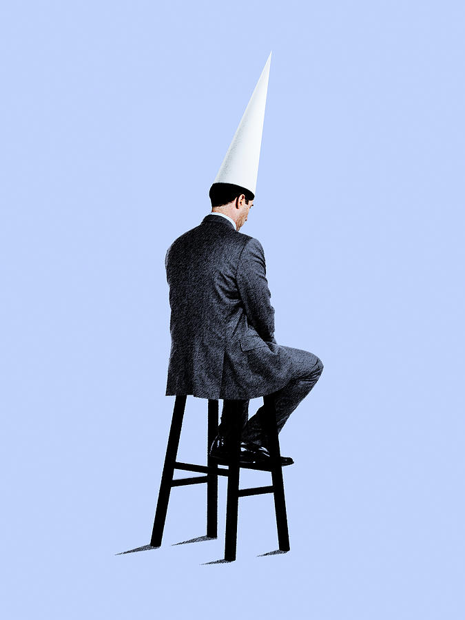 Businessman Sitting On Stool Wearing Dunce Cap Photograph by Dny59