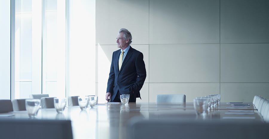 Businessman standing alone in conference room Photograph by Martin Barraud