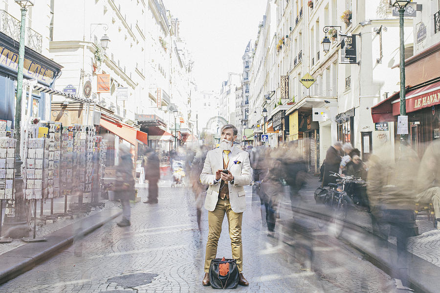 Businessman standing amidst crowd moving on street Photograph by Xavierarnau