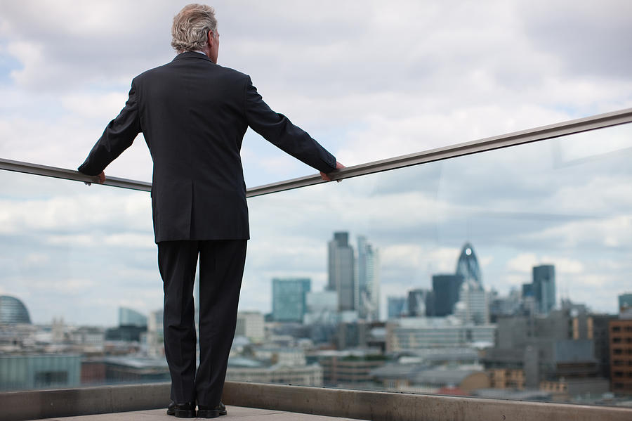Businessman standing on urban balcony Photograph by Tom Merton