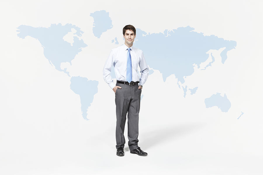 Businessman standing with world map. Photograph by Ezra Bailey