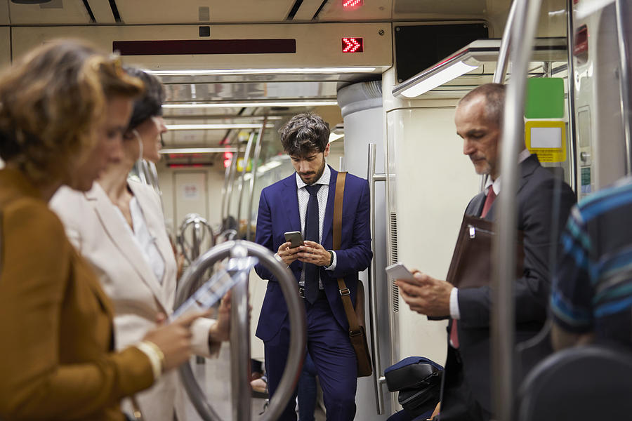 Businessman using cell phone on subway train Photograph by Compassionate Eye Foundation/Morsa Images