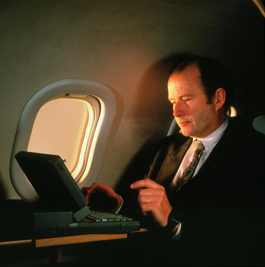 Businessman Using Laptop Computer On An Aeroplane Photograph by Cc Studio/science Photo Library