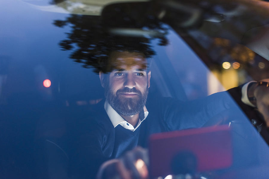 Businessman using navigation device in car at night Photograph by Westend61