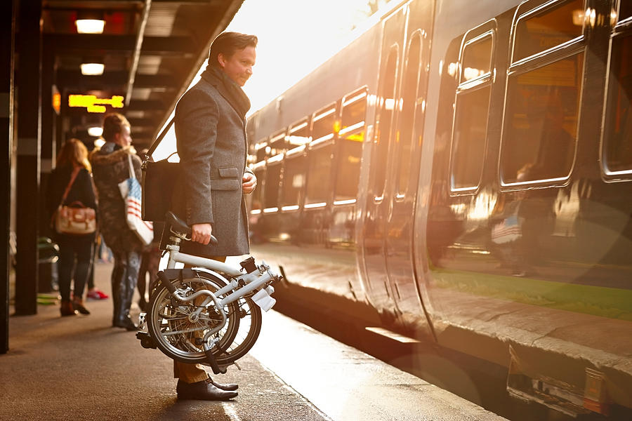 Businessman with folding cycle boarding train Photograph by Dean Mitchell