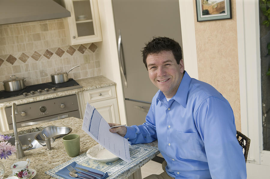 Businessman with paperwork at home Photograph by Comstock Images