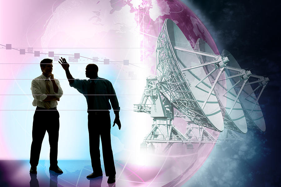 Businessmen presenting chart with satellites and globe in background Photograph by Comstock