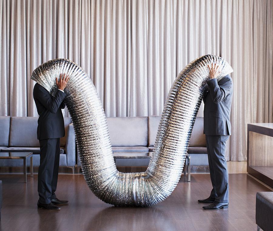 Businessmen with their heads inside metal tubing Photograph by Martin Barraud