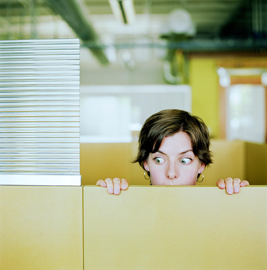 Businesswoman peering over cubicle wall Photograph by Karen Moskowitz