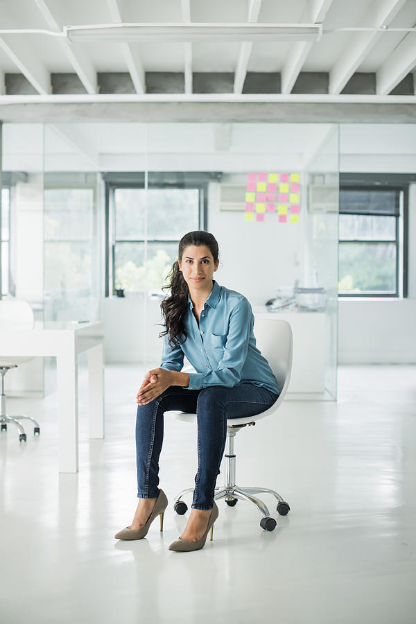 Businesswoman sitting on a chair in open office Photograph by Portra