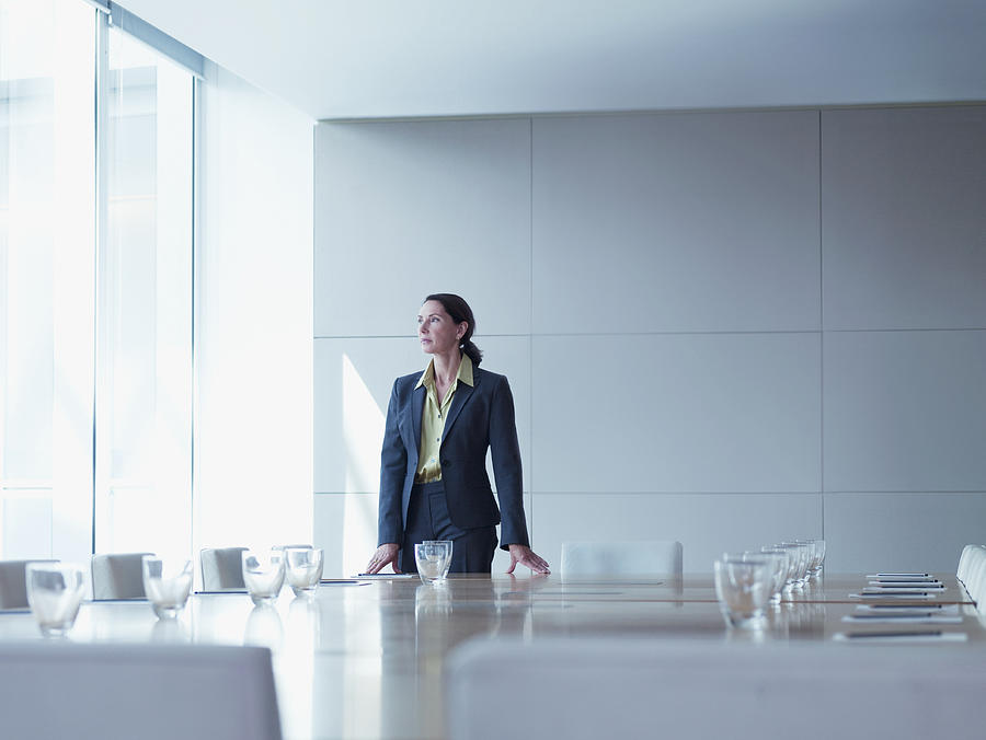 Businesswoman standing alone in conference room Photograph by Martin Barraud