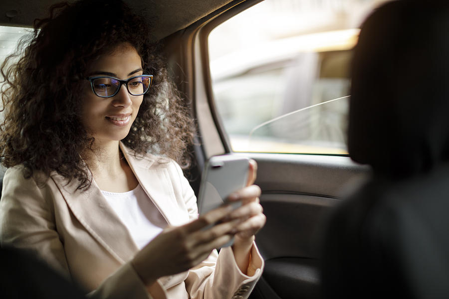 Businesswoman using smart phone in a car Photograph by Damircudic