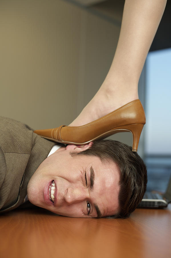 Businesswomans high heeled shoe on businessmans head Photograph by Stock4b-rf