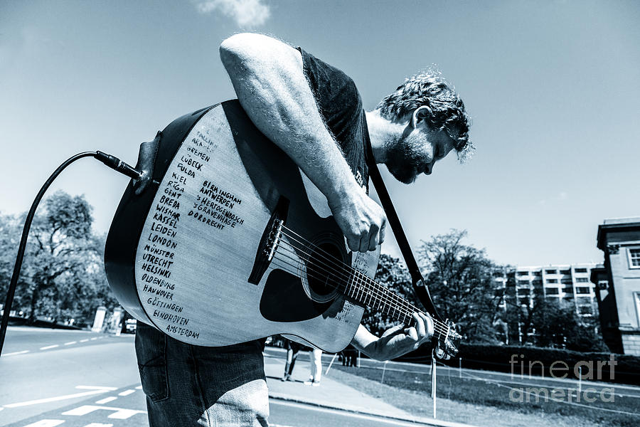 Busking musician with amplified acoustic guitar list of places v Photograph by Peter Noyce
