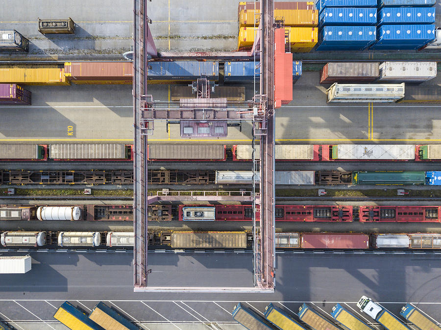 Cargo trains, trucks and a huge crane at freight terminal, Austria Photograph by Guenterguni