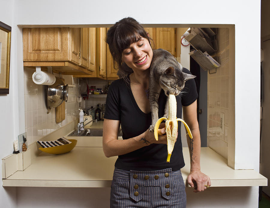 Cat eating banana on womans shoulder Photograph by Allen Simon