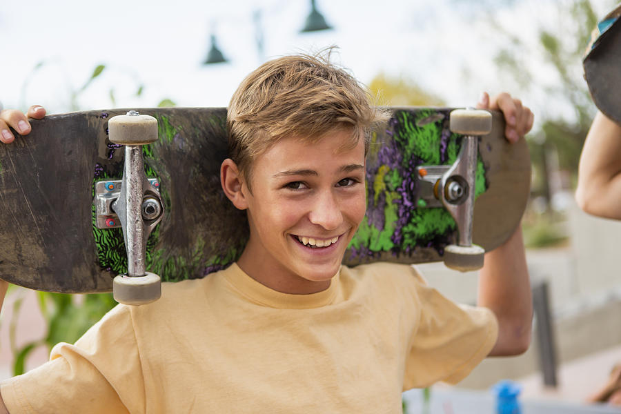 Caucasian boy holding skateboard outdoors Photograph by Marc Romanelli