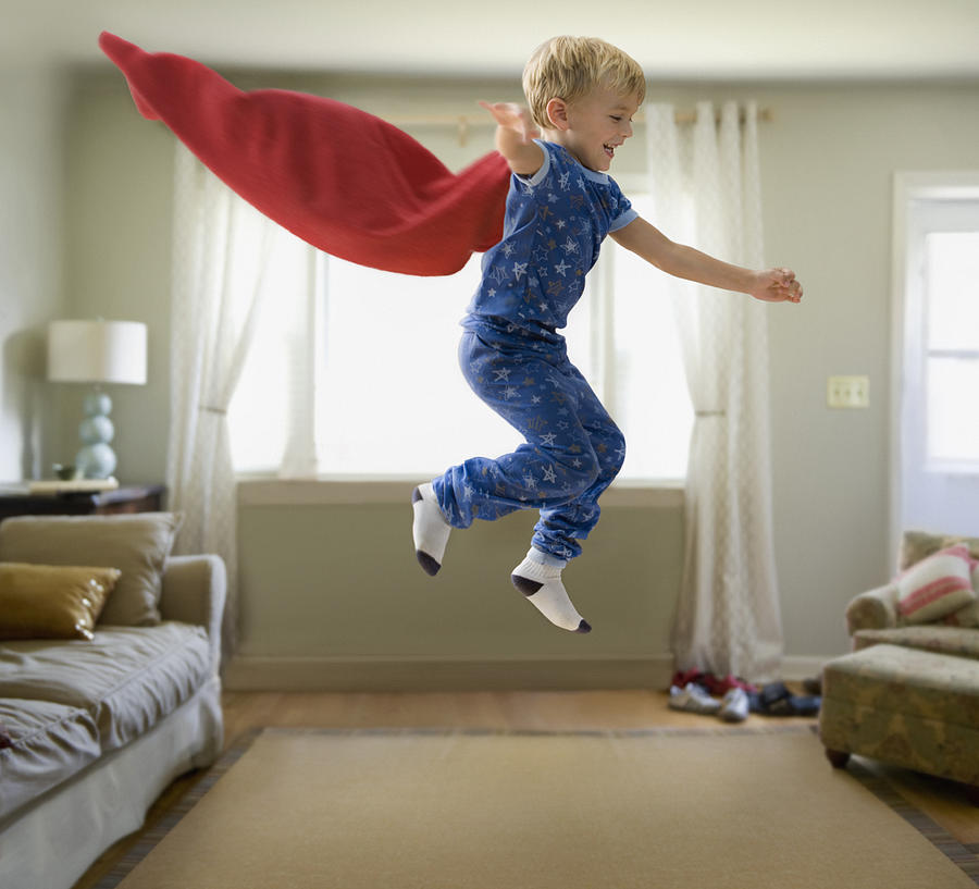 Caucasian boy in superhero costume jumping through the air Photograph by Jose Luis Pelaez Inc