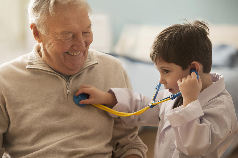 Caucasian boy listening to grandfathers heartbeat with stethoscope Photograph by Jose Luis Pelaez Inc