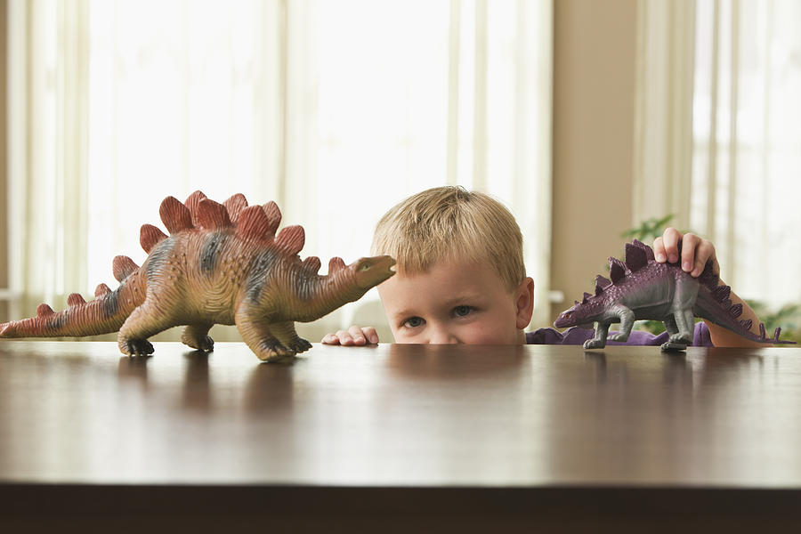 Caucasian boy playing with toy dinosaurs Photograph by Jose Luis Pelaez Inc
