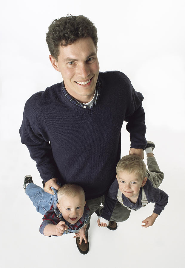 Caucasian Brown Haired Single Father Holds Two Young Sons By Their Pants Laughing Photograph by Photodisc