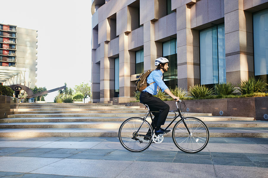 Caucasian businessman riding bicycle outside office building Photograph by Peathegee Inc