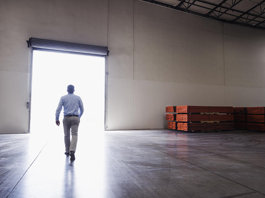 Caucasian businessman walking in warehouse Photograph by Erik Isakson