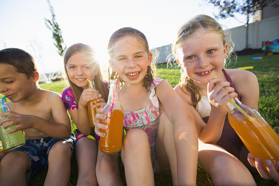 Caucasian children drinking soda in backyard Photograph by Mike Kemp