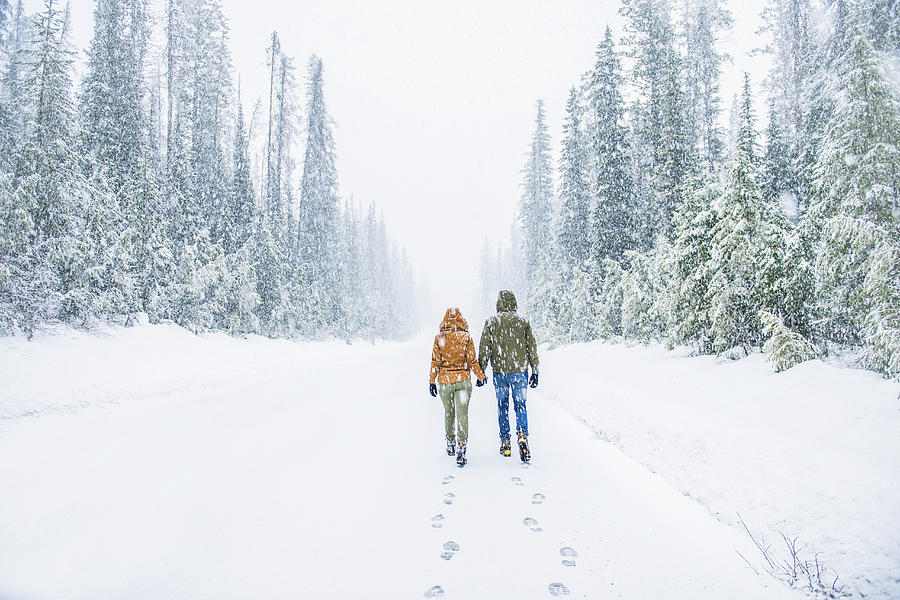 Caucasian couple walking on snowy forest road Photograph by Jacobs Stock Photography Ltd