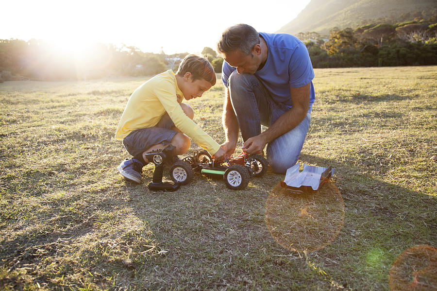 Caucasian father and son playing with remote control cars in field Photograph by Resolution Productions