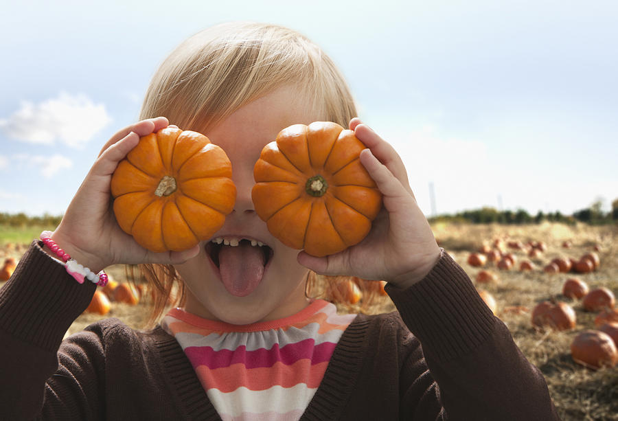 Caucasian girl covering eyes with small pumpkins Photograph by Jose Luis Pelaez Inc