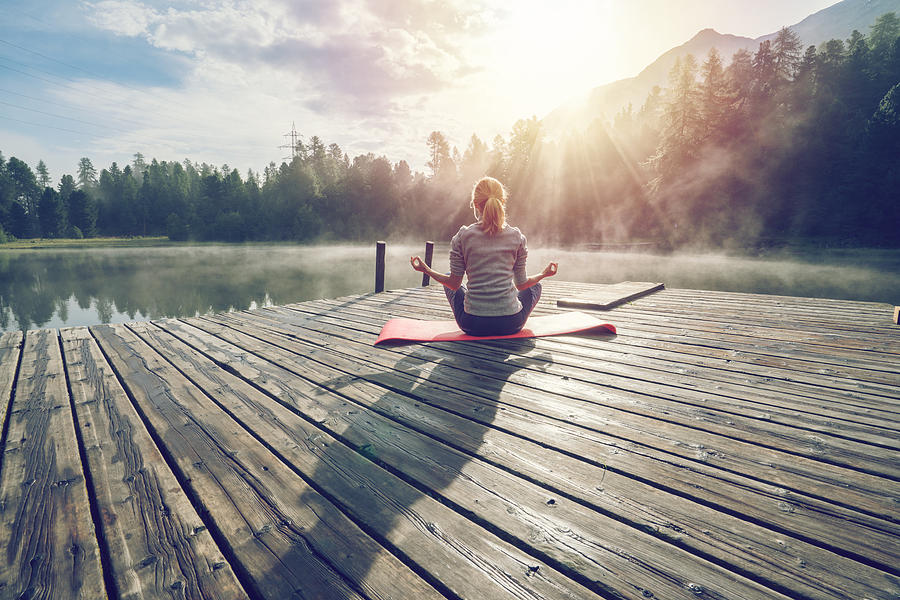 Caucasian girl exercising yoga in nature, morning by the lake in Switzerland Photograph by Swissmediavision