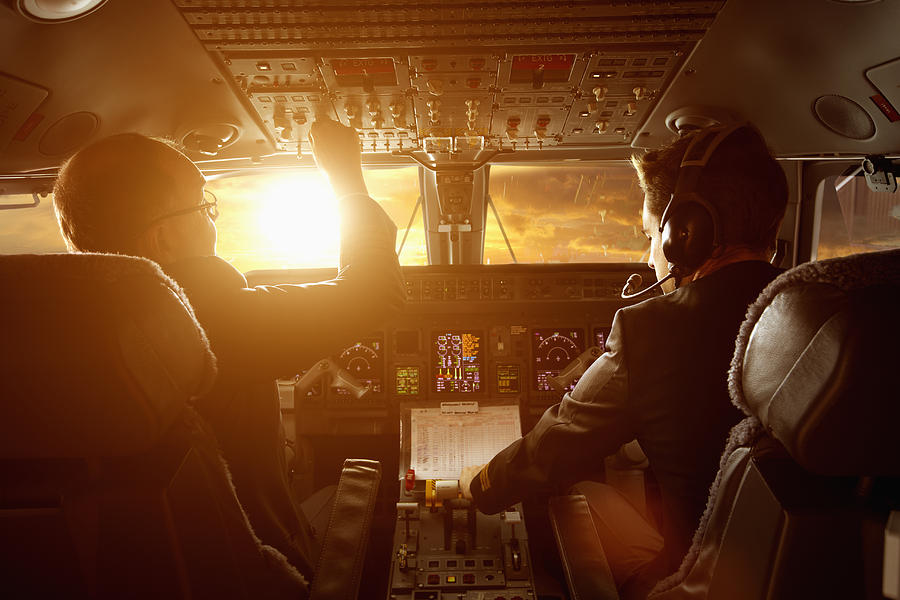 Caucasian pilots flying jet at sunset Photograph by Colin Anderson Productions pty ltd