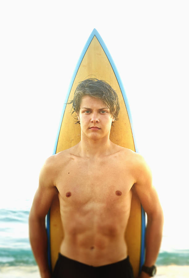 Caucasian teenage boy standing with surfboard on beach Photograph by Colin Anderson Productions pty ltd