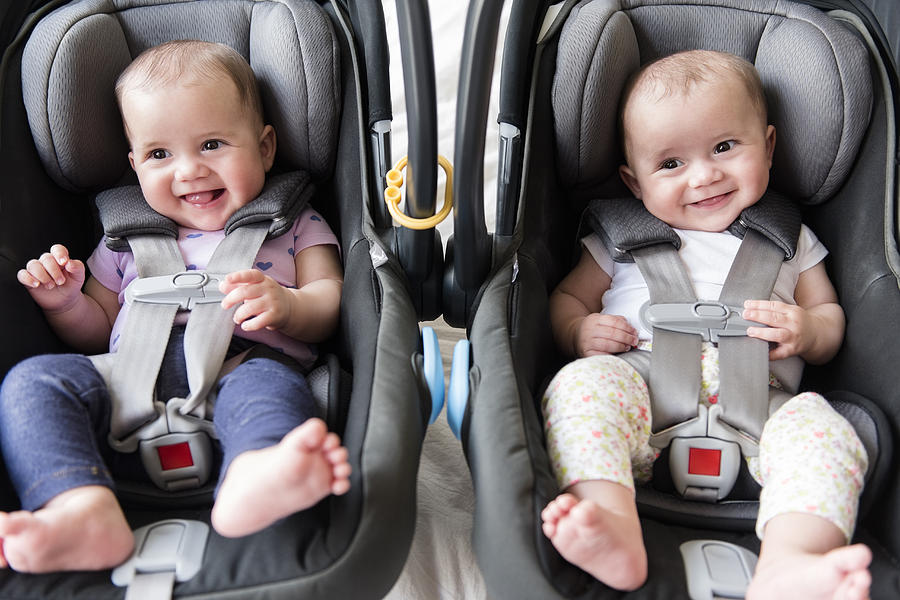 Caucasian twin baby girls in car seats Photograph by JGI/Jamie Grill