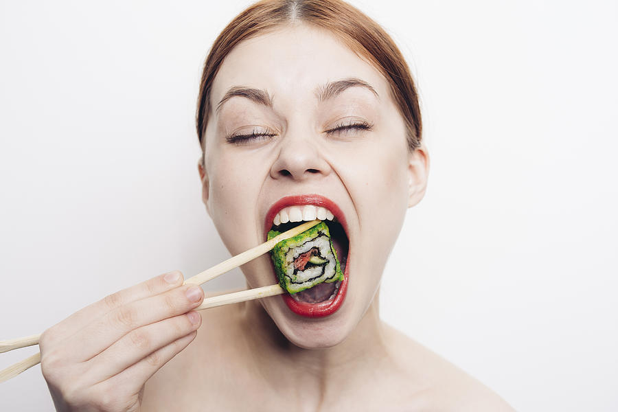 Caucasian woman eating sushi with chopsticks Photograph by Dmitry Ageev