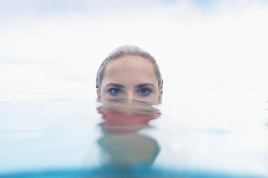 Caucasian woman peering over swimming pool water surface Photograph by Jacobs Stock Photography Ltd