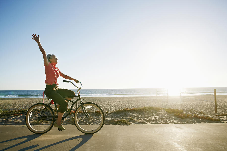 Caucasian woman riding bicycle near beach Photograph by Peter Griffith