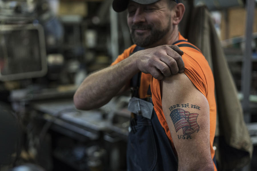 Caucasian worker displaying tattoo in factory Photograph by Jetta Productions Inc