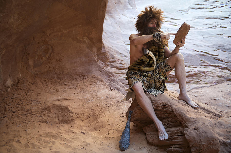 Caveman Sitting Outdoors Using Stone Tablet with Touchscreen Photograph by PeskyMonkey