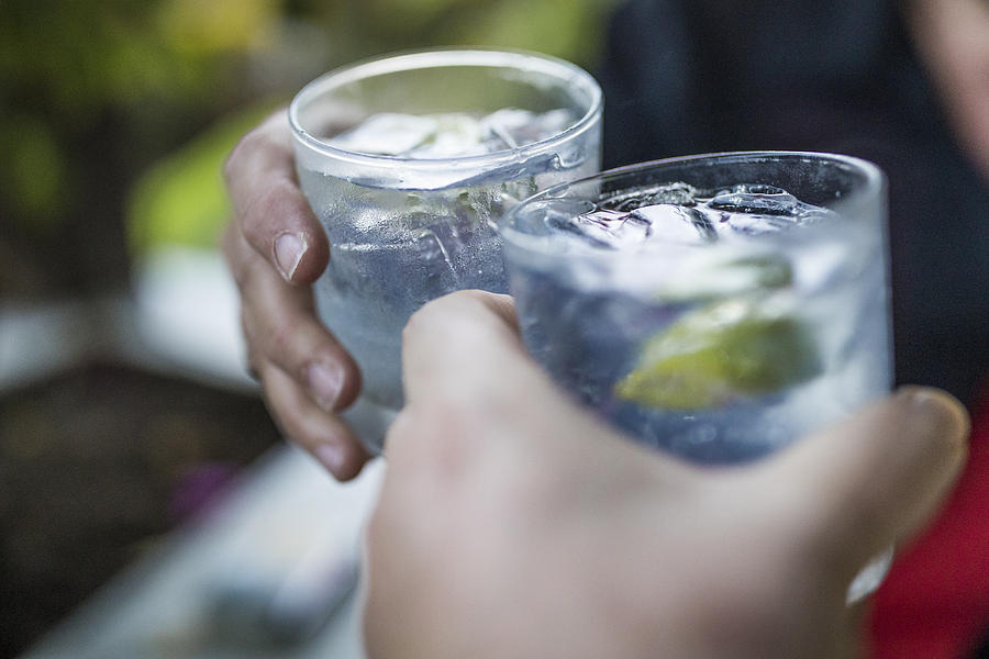 Celebration concept with hand close-up of a couple celebrating the beginning of their vacations with each a gin & tonic. Photograph by Instants