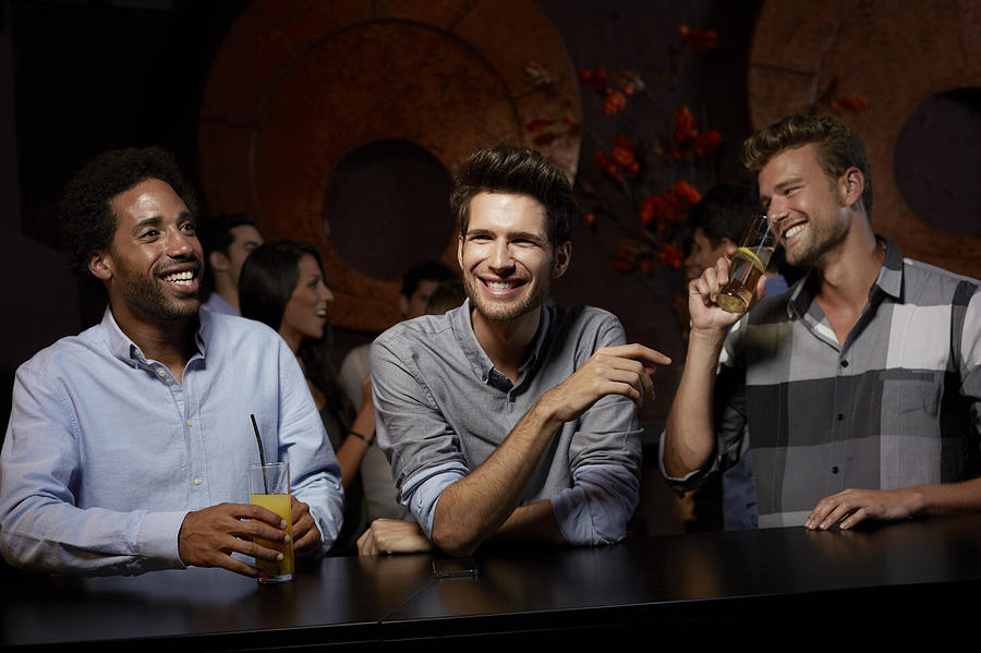 Cheerful friends enjoying drinks in nightclub Photograph by Morsa Images