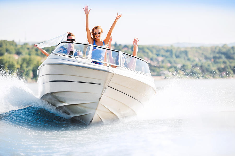 Cheerful young people riding in a speedboat Photograph by Skynesher
