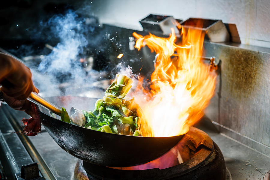 Chef in restaurant kitchen at stove with high burning flames Photograph by Ansonmiao