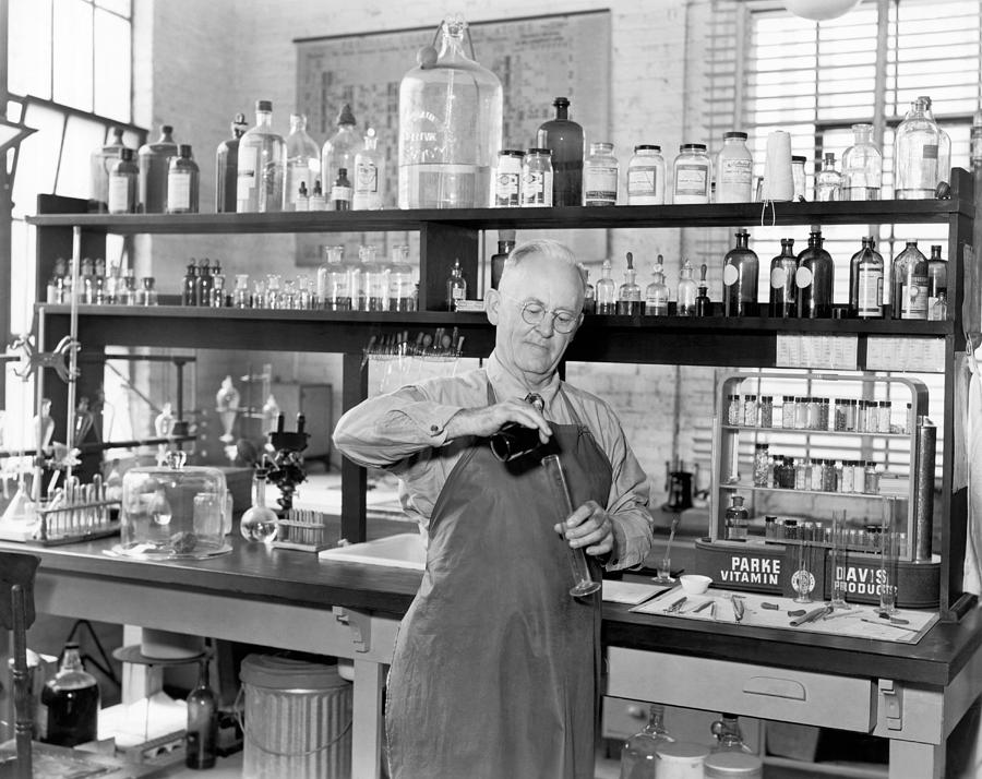 Bottle Photograph - Chemist Working In A  Lab by Underwood Archives