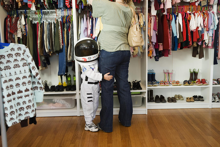 Child (4-5 yeras) wearing space costume hugging mothers leg in shop Photograph by Inti St. Clair