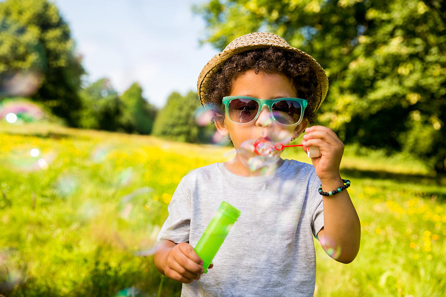 Child blowing bubbles in park Photograph by Wundervisuals