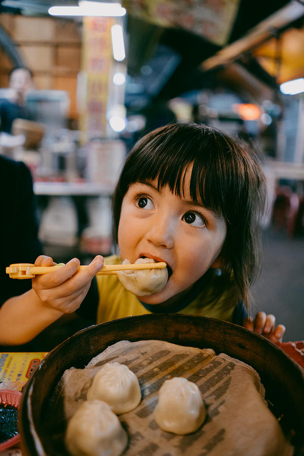 Child eating xiaolongbao at night market, Taiwan Photograph by Ippei Naoi
