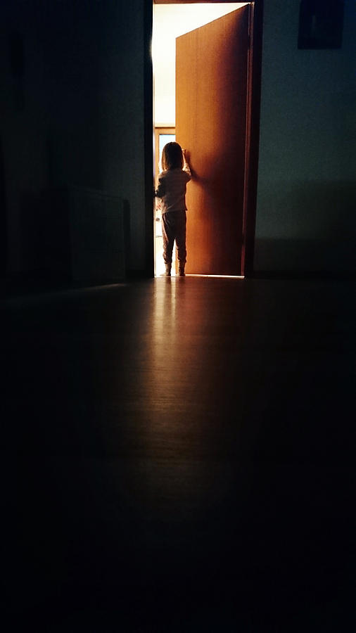 Child in a dark hallway, opening a door into the light Photograph by Elva Etienne