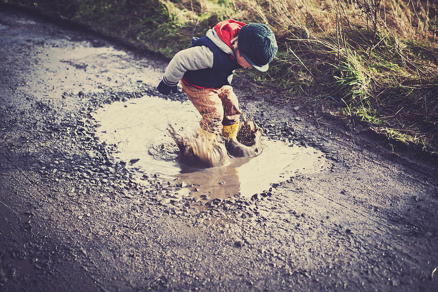 Child jumping in a puddle Photograph by Sally Anscombe